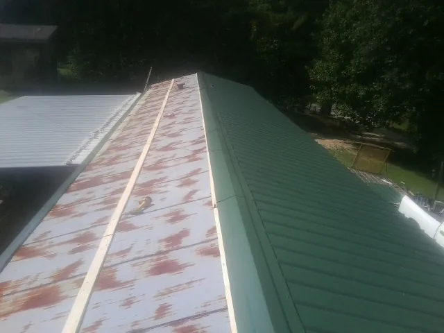 Old rusted panels beside newly installed green metal roofing — Wind Damage Roof Repair by Roofing Brothers in Bradenton