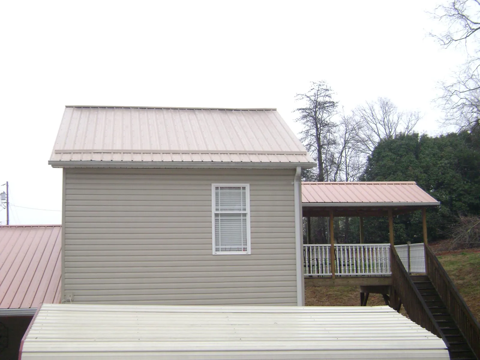 Tan metal roofs on a two story addition and attached porch, from a Roof Replacement job in Bradenton