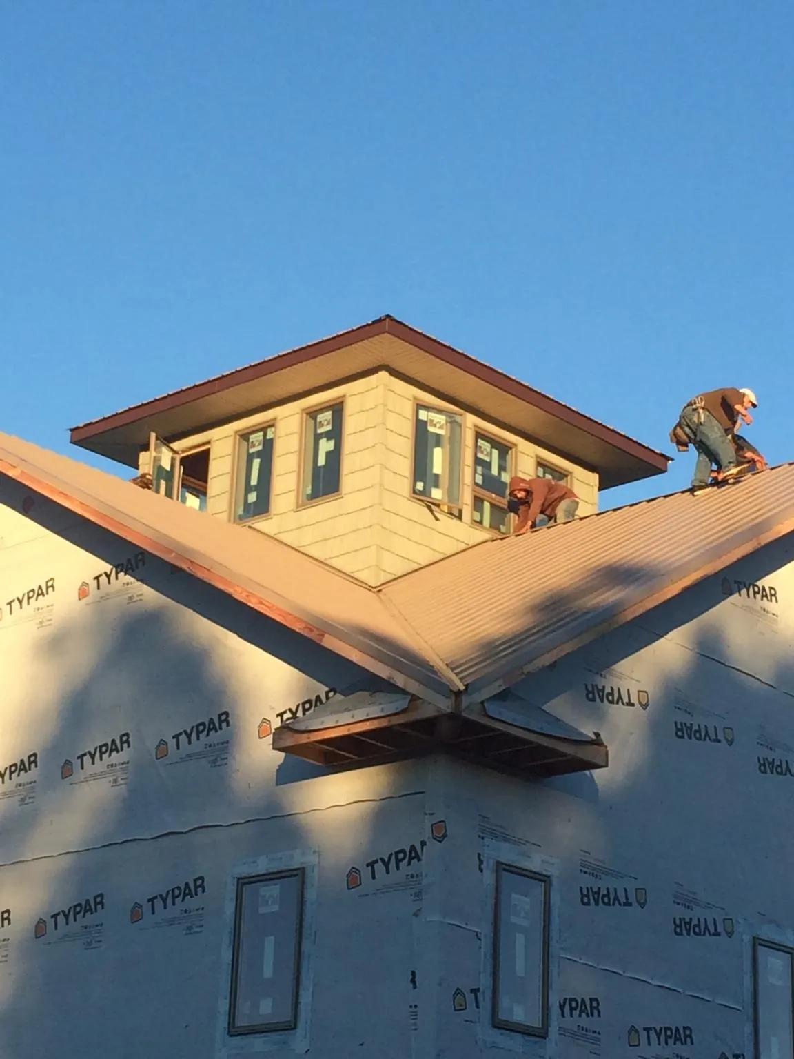 Roofers working around a rooftop cupola on a new metal roof at sunset — Roof Waterproofing in Bradenton by Roofing Brothers